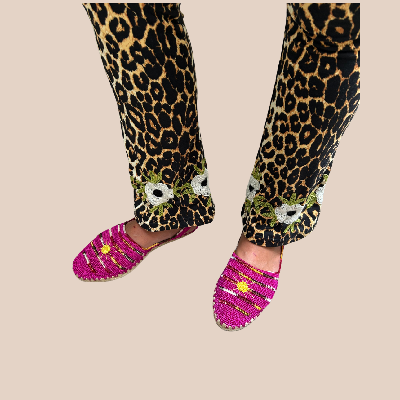 Black leopard-print leggings in polyester and spandex with hand-embroidered white flowers at the ankle. Slightly flared at the ankle.
