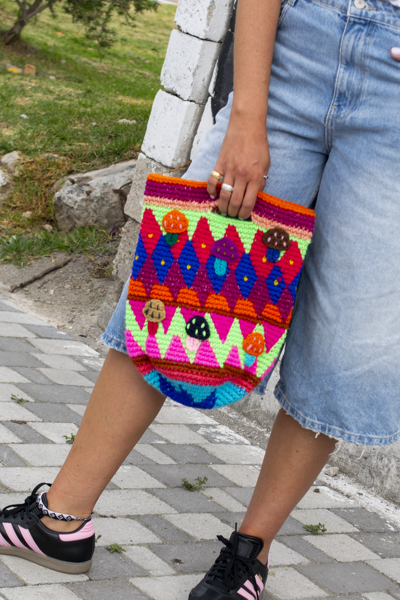 Bucket bag with integrated handles and multicolored mushroom patterns.