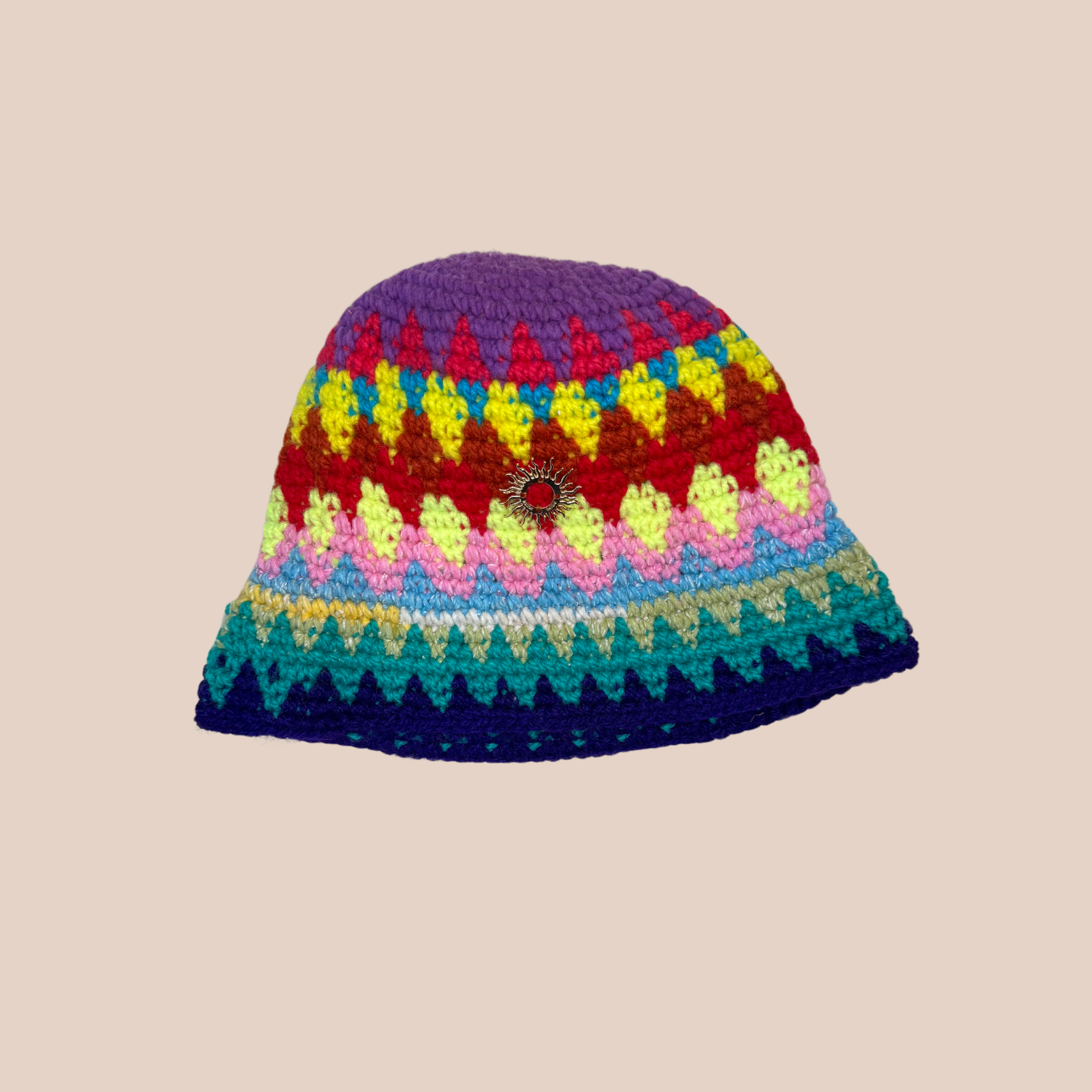 Image d'un bucket hat crocheté en laine et acrylique, arborant des couleurs vives et audacieuses, médaillon soleil cousue main
