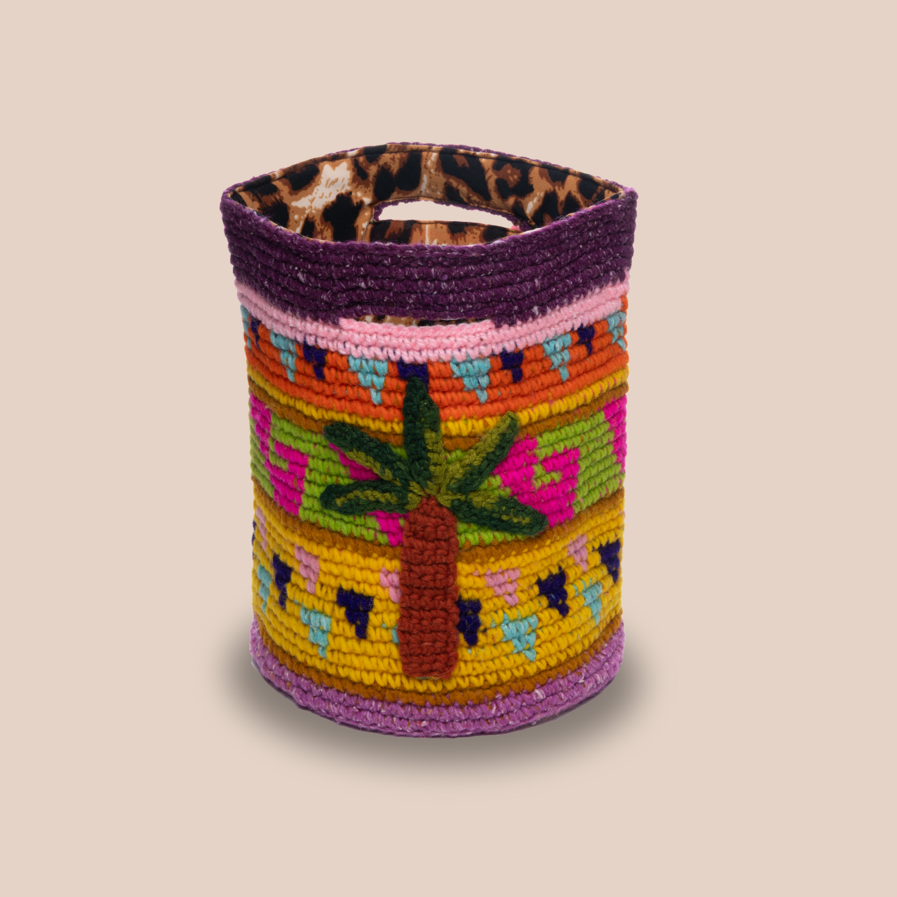 Image d'un sac aux motifs palmiers avec doublure léopard, sac en laine crochetée arborant des couleurs vives et audacieuses