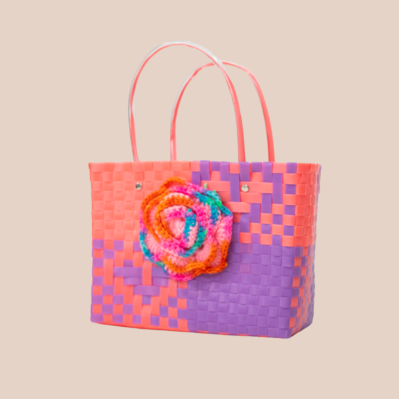 Handmade recycled plastic bag in pink and purple, featuring a large multicolored crocheted flower.