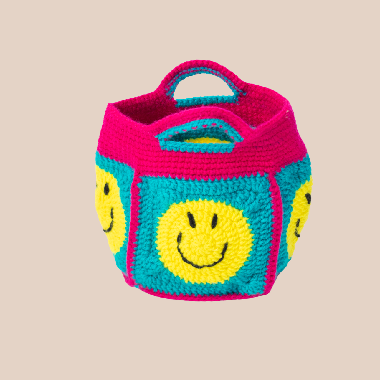 Small rounded bag with yellow smiley patterns.
Turquoise base and integrated pink handles.