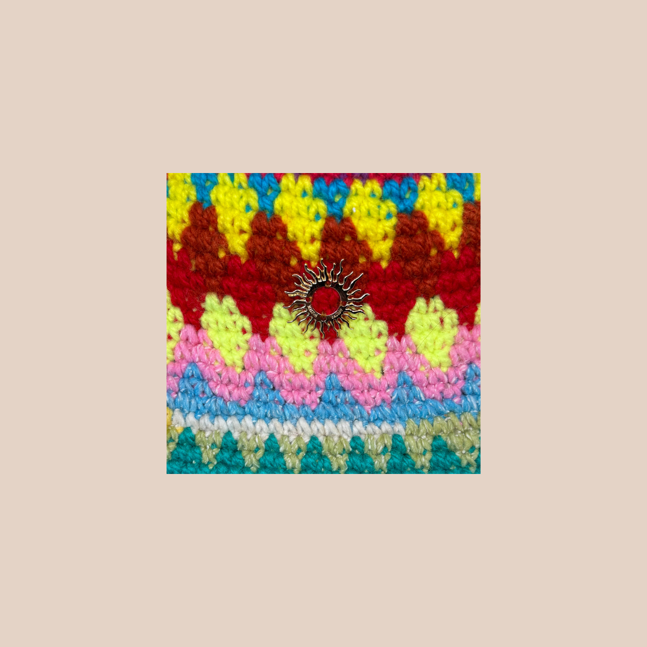 Image zoomée d'un bucket hat crocheté en laine et acrylique, arborant des couleurs vives et audacieuses, médaillon soleil cousue main
